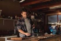 Homem caucasiano fabricante de facas em pé na mesa, preparando faca na oficina. artesão independente de pequenas empresas no trabalho. — Fotografia de Stock