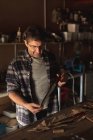 Homem caucasiano fabricante de facas em pé na mesa, preparando faca na oficina. artesão independente de pequenas empresas no trabalho. — Fotografia de Stock