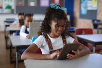 Ragazza afroamericana che usa tablet digitale mentre è seduta sulla scrivania in classe a scuola. concetto di scuola e istruzione — Foto stock