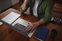 Midsection de homem na cozinha sentado à mesa usando laptop e escrever notas. tecnologia e comunicação, trabalho flexível de casa. — Fotografia de Stock