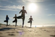 Группа разнообразных подруг практикующих йогу на пляже. здоровый активный образ жизни, фитнес на открытом воздухе и благополучие. — стоковое фото