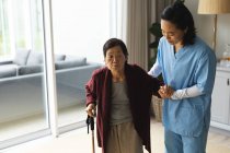 Asiatische Physiotherapeutin behandelt ältere Patientinnen zu Hause. Gesundheitswesen und medizinische physiotherapeutische Behandlung. — Stockfoto