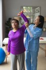 Asian female physiotherapist treating asian female patient at her home. healthcare and medical physiotherapy treatment. — Stock Photo