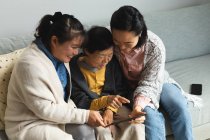 Feliz sênior asiático mulher em casa com adulto filha e neta usando tablet. estilo de vida sênior, passar tempo em casa com a família. — Fotografia de Stock