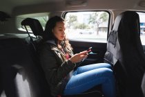 Sorridente donna asiatica seduta in taxi, utilizzando smartphone. indipendente giovane donna in giro per la città. — Foto stock
