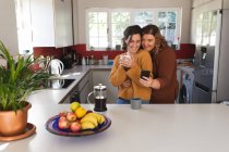 Couple lesbien souriant et buvant du café dans la cuisine. mode de vie domestique, passer du temps libre à la maison. — Photo de stock