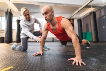 Caucasian female trainer instructing man exercising at gym, doing press ups. strength and fitness cross training for boxing. — Stock Photo