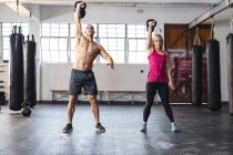Сильные кавказские мужчина и женщина занимаются в спортзале, поднимают тяжести. силовые и фитнес-кросс тренировки для бокса. — стоковое фото