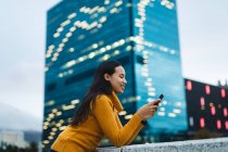Asian woman using smartphone and smiling in the street. independent young woman out and about in the city. — Stock Photo