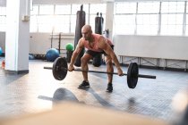 Hombre caucásico fuerte haciendo ejercicio en el gimnasio, levantando pesas. entrenamiento cruzado de fuerza y fitness para boxeo. - foto de stock