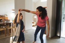 Happy mixed race mother and daughter dancing in living room. domestic lifestyle and spending quality time at home. — Stock Photo