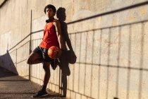 Fit afrikanisch-amerikanischer Mann, der in der Stadt Basketball auf der Straße hält. Fitness und aktiver urbaner Lebensstil im Freien. — Stockfoto