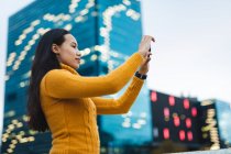 Donna asiatica scattare foto con smartphone in strada. indipendente giovane donna in giro per la città. — Foto stock