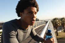 Жирний афроамериканець, що займається фізичними вправами в місті, відпочиває і п'є воду. Фітнес і активне вуличне життя. — стокове фото