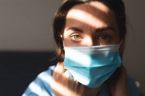 Retrato de doctora caucásica usando mascarilla y mirando a la cámara. servicios médicos y sanitarios durante la pandemia de coronavirus covid 19. - foto de stock