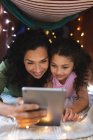 Portrait of happy mixed race mother and daughter using laptop in makeshift tent. domestic lifestyle and spending quality time at home. — Stock Photo