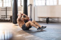 Hombre caucásico fuerte haciendo ejercicio en el gimnasio, haciendo abdominales. entrenamiento cruzado de fuerza y fitness para boxeo. - foto de stock