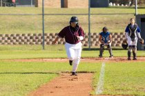 Смешанная раса женщина бейсболистка на солнечном бейсбольном поле работает между базами во время игры. женская бейсбольная команда, спортивная подготовка и тактика игры. — стоковое фото