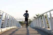 Ajuste hombre afroamericano ejerciendo en la ciudad corriendo en la calle. fitness y estilo de vida urbano activo al aire libre. - foto de stock