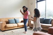 Glückliche gemischte Rasse Mutter und Tochter tanzen im Wohnzimmer. Lebensstil und hochwertige Zeit zu Hause verbringen. — Stockfoto