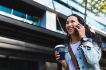 Mulher asiática usando smartphone e segurando takeaway café na rua. jovem independente para fora e sobre na cidade. — Fotografia de Stock