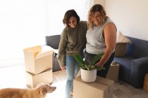 Lesbian couple with dog smiling and embracing during moving house. domestic lifestyle, spending free time at home. — Stock Photo