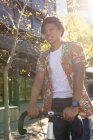 Hombre afroamericano en la ciudad sonriendo y sosteniendo su bicicleta. nómada digital sobre la marcha, fuera y alrededor de la ciudad. - foto de stock