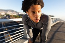 Uomo afro-americano in forma che si esercita in città riposando in strada. fitness e stile di vita urbano attivo all'aperto. — Foto stock