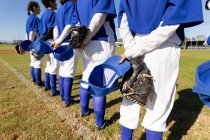 Vielfältige Gruppe von Baseballspielerinnen, die vor dem Spiel mit den Händen hinter dem Rücken auf dem Feld stehen. Baseballmannschaft, Sporttraining, Zusammenhalt und Engagement. — Stockfoto