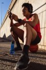 Подходит африканский американец, тренирующийся в городе, используя смартфон на улице. фитнес и активный городской уличный образ жизни. — стоковое фото