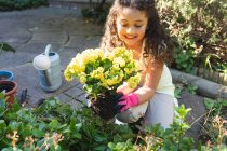 Sorrindo menina de raça mista plantando flores no quintal. estilo de vida doméstico e passar tempo de qualidade em casa. — Fotografia de Stock