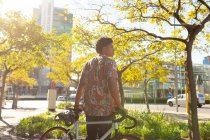Африканський американець у місті, який дивиться убік і тримає свій велосипед. Цифровий кочівник у русі, десь у місті.. — стокове фото