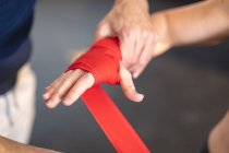 Entraîneur masculin instruisant femme faisant de l'exercice au gymnase, enveloppant les mains avec du ruban adhésif. musculation et fitness cross training pour la boxe. — Photo de stock