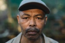 Retrato de hombre afroamericano jardinero mirando a la cámara en el centro del jardín. especialista en vivero de plantas bonsái, empresa hortícola independiente. - foto de stock