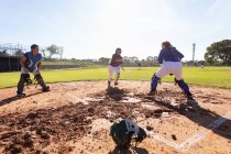 Vielfältige Gruppe von Baseballspielerinnen in Aktion auf dem sonnigen Baseballfeld während des Spiels. Baseballteam der Frauen, Sporttraining und Spieltaktik. — Stockfoto
