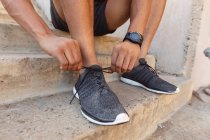 Hombre en forma haciendo ejercicio en la ciudad atando zapatos. fitness y estilo de vida urbano activo al aire libre. - foto de stock