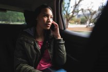 Asiatin sitzt im Taxi und telefoniert auf dem Smartphone. Unabhängige junge Frau in der Stadt unterwegs. — Stockfoto