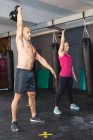 Hombre y mujer caucásicos fuertes que hacen ejercicio en el gimnasio, levantando pesas. entrenamiento cruzado de fuerza y fitness para boxeo. - foto de stock