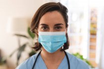 Портрет белой женщины-врача в маске и смотрящей в камеру. медицинские и медицинские услуги во время пандемии коронавируса. — стоковое фото