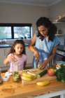 Feliz madre mestiza e hija cocinando juntas en la cocina. estilo de vida doméstico y pasar tiempo de calidad en casa. - foto de stock