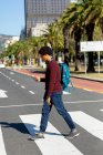Homem afro-americano na cidade usando smartphone e caminhando. nômade digital em movimento, para fora e sobre na cidade. — Fotografia de Stock