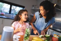 Happy mixed race mother and daughter cooking together in kitchen. domestic lifestyle and spending quality time at home. — Stock Photo