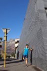 Ajuste hombre afroamericano haciendo ejercicio en la ciudad que se extiende en la calle. fitness y estilo de vida urbano activo al aire libre. - foto de stock