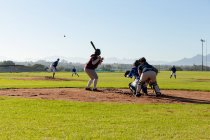 Diverso grupo de jugadoras de béisbol en acción en el campo de béisbol soleado durante el juego. equipo femenino de béisbol, entrenamiento deportivo y tácticas de juego. - foto de stock