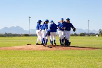 Різноманітна група щасливих гравців у бейсбол, що святкують на сонячному бейсбольному полі після гри. жіноча бейсбольна команда, спортивне тренування, взаємопочуття та прихильність . — стокове фото