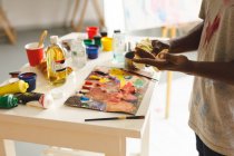 Afrikanischer männlicher Maler bei der Arbeit beim Händewaschen im Kunstatelier. Kreation und Inspiration im Malatelier eines Künstlers. — Stockfoto