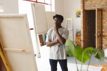 Pittore afroamericano di sesso maschile al lavoro guardando opere d'arte in studio d'arte. creazione e ispirazione in uno studio di pittura artisti. — Foto stock