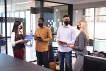 Grupo diverso de colegas de negócios usando máscaras faciais e tendo reunião. trabalhando em negócios em um escritório moderno durante coronavírus covid 19 pandemia. — Fotografia de Stock