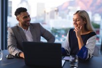 Zwei unterschiedliche männliche und weibliche Geschäftskollegen, die sich unterhalten und Laptop benutzen. Arbeit in einem modernen Büro. — Stockfoto