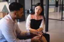 Diverse male and female business colleagues using tablet and talking. working in business at a modern office. — Stock Photo